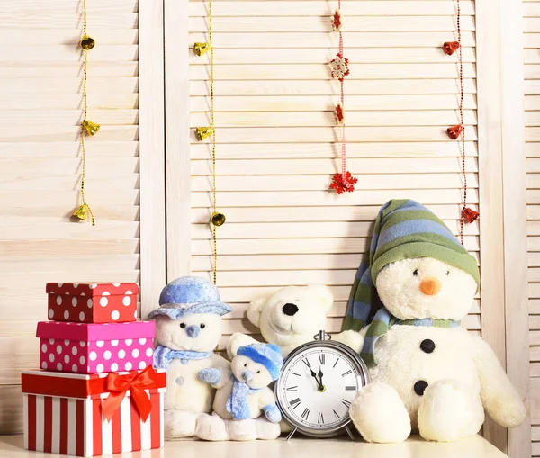 Snowmen, teddy bears and present boxes near alarm clock