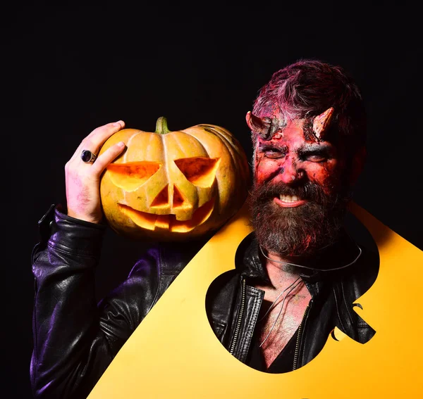 Concepto fiesta de Halloween. El hombre que usa maquillaje aterrador sostiene calabaza tallada — Foto de Stock