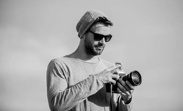 Manual settings. Guy photographer outdoors sky background. Hipster reporter taking photo. Photojournalist concept. Travel blogger. Professional photographer. Handsome photographer guy retro camera