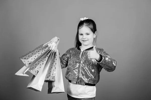 Dívka s nákupní tašky fialové pozadí. Nakupování a nákup. Černý pátek. Sleva na prodej. Nákupní den. Dítě drží balíky. Dětská móda. Překvapivý dárek. Skvělé obchody. Skvělá volba — Stock fotografie