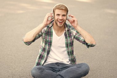 gerçek mutluluk. serbest zaman. online eğitim. müzik dinleyin. ebook kavramı. adam damalı gömlek. öğrenci rahatlayın kulaklık kullanın. mutlu adam açık. adam yere otur. kulaklıkta kaygısız öğrenci