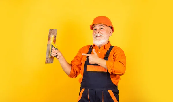 Prozess des Auftragens von Spachtelmasse. Putzwerkzeuge für Putz. Gipskellen-Spachtel auf gelbem Gipskarton. Gipser in Arbeitsuniform Putzwand im Innenbereich. Mann mit Spachtel — Stockfoto