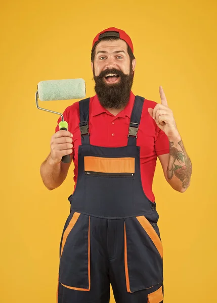 Creative idea. inspired engineer designer ready to paint wall. repair concept. bearded man worker with roller tool. hipster builder in cap yellow background. erector assistant in work uniform — ストック写真
