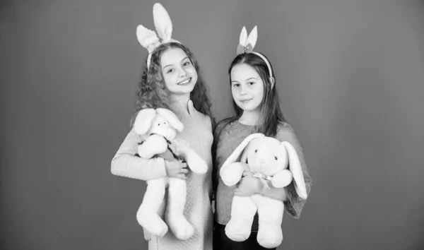 Hoop liefde en vreugdevolle leven. Kinderen met Bunny speelgoed op blauwe achtergrond. Sisters glimlachen schattige Bunny kostuums. Verspreid vreugde en geluk rond. Vrienden kleine meisjes met bunny oren vieren Pasen — Stockfoto