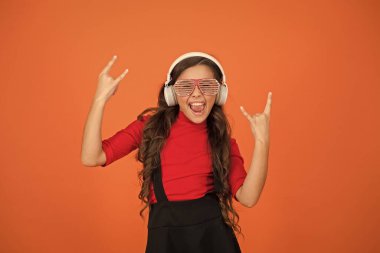 Parti aksesuarı. Eğleniyorum. Parti için çalma listesi. Müzik konsepti. Çocuk gözlük takıyor. Göz giysisi mağazası. Güzel parça. Gözlüklü, turuncu arka planda bir kız. Etkinlik ve eğlence. Parti kızı.