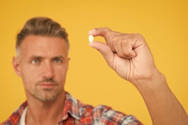 Elimde vitamin hapı var. Yan etkiler. İlaç konsepti. Kenevir türevi CBD. Erkek sağlığı için gıda katkı maddeleri. Vitamin kompleksi. Yakışıklı, olgun bir adam ürününü sunuyor. Uyuşturucu hapları yakında.