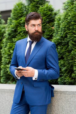 Her zaman müsait. Gelecekteki işvereniniz. Yakışıklı müdür akıllı telefon kullanır. Dışarıda resmi kıyafetli bir adam var. Emlakçı ceketi. Modern yaşam konsepti. Özgüvenin portresi. Başarılı sigorta aracı