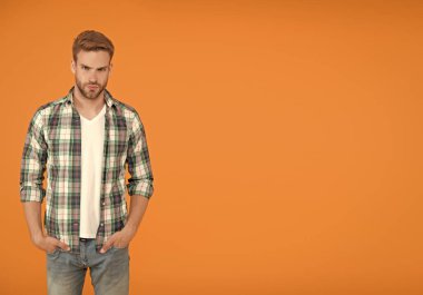 Seni iyi gösterecek. kopyalama alanı. Erkekler için sıradan moda. Erkeksi kıyafetler ve bak. Şık giyinmiş şık bir erkek. Kareli gömlek ve kot pantolon giymiş yakışıklı bir adam. öğrenci turuncu arka planı