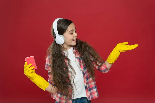 Everything is better with music. Cleaning party. Girl wear headphones and protective gloves for cleaning. Listening music and cleaning. Make household more joyful. Harmless cleaner simple ingredients
