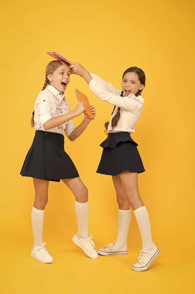 Schoolgirls fight. outraged classmates with workbook. girls cant share a book. kids learning grammar. back to school. information. love reading. childrens literature. small girls in school uniform — Stock Photo, Image