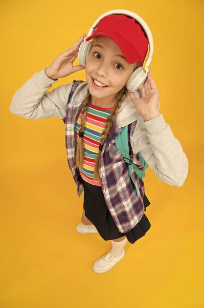 Lindo adolescente hipster escuchar música auriculares fondo amarillo. Una colegiala genial. Moda de adolescentes. Adolescente alegre. Pequeña niña de pelo largo. Estilo de vida adolescente. Adolescente moderno. Feliz infancia. — Foto de Stock