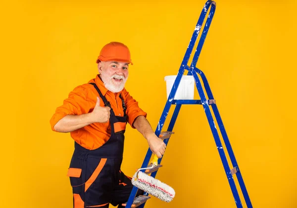 man in working clothes painting wall in empty room. painter in overall and cap with paint bucket. builder worker painting facade. thermal insulation works. Painter man staircase. To make repairs