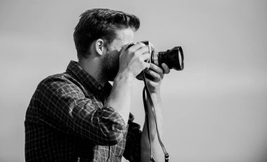Antika ekipmanlar. Hippi fotoğrafçı. Blogger video blogu çekiyor. Adam açık havada gökyüzü arka planında. Yakışıklı blogcu, gezgin, geçmişe dönük kamera. Gazeteci fotoğraf çekiyor. Elle ayarlar. Seyahat blogçusu