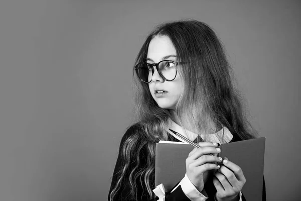 Sê esperto. Menina inteligente fundo marrom. A menina voltou para a escola. Menina pequena ler livro em óculos. Menina da escola primária com cabelo longo. Escola e educação, espaço de cópia — Fotografia de Stock