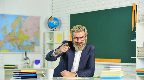 Giorno della conoscenza. Insegnante di scuola maschile seduto in classe. Bel educatore maturo e intelligente. Garantire l'idoneità della tesi per la presentazione. Documenti cartacei. Compiti scolastici. Ritorno a scuola — Foto Stock