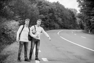 Sırt çantaları yolda beraber yürüyorlar. Yol boyunca yürüyen ikizler. Macera ve keşif. Sırt çantalı bir adam yolda otostop çekiyor. Yaz tatili. Turist gezgini otomobil durağında durur. Bütçe yolcuları