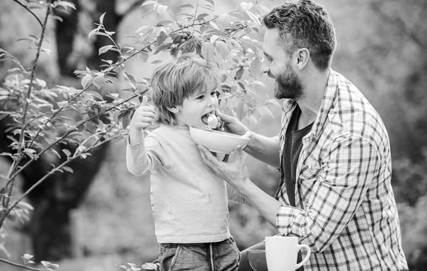 Familie und Elternschaft. Sohn und Vater essen. Glücklicher Vatertag. Kleiner Junge mit Papa isst Müsli. Morgens Frühstück. gesunde Ernährung und Ernährung. Milchprodukte. Nur frische und gesunde Nahrung für mein Baby — Stockfoto