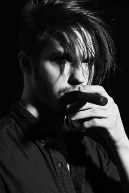 Ciddi sakallı adam puro içiyor.