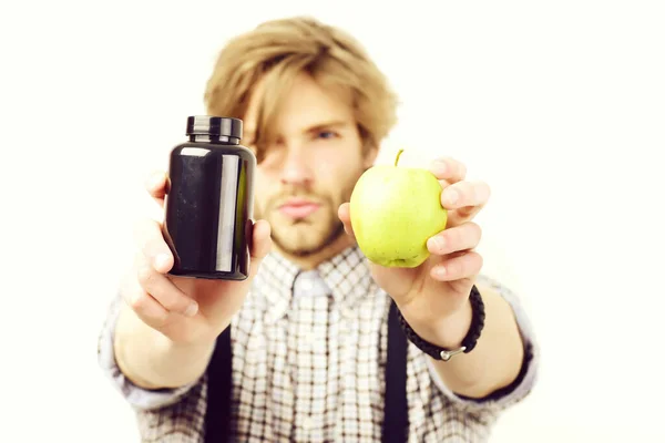 Hombre con barba y peinado elegante sostiene manzana y pastillas — Foto de Stock