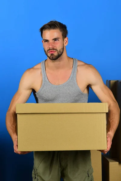 Karton kutuların arasında duran ve elinde bir tane tutan bir adam. — Stok fotoğraf