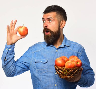 Şaşırmış suratlı çiftçi kırmızı elma tutuyor. Sakallı adam