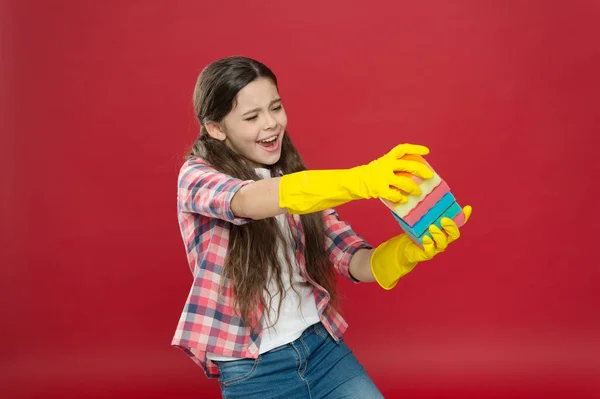 Hausmeisterpflichten. Geschirr spülen. Verwandeln Sie das Putzen in Spiel. Sauberkeit einimpfen. Reinigung mit Schwamm. Putzmittel. Mädchen Gummihandschuhe zum Putzen halten bunte Schwämme. Putzen könnte Spaß machen — Stockfoto