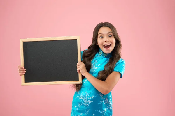 Menina feliz segurar blackboard fundo rosa. criança alegre segurar placa de publicidade. Uma criança da escola na aula. Quadro negro para texto publicitário, espaço de cópia. Voltar para a escola campaig marketing — Fotografia de Stock