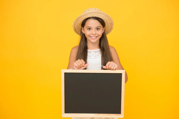 Anúncio e informação. menina elegante tropical com bordo. espaço de cópia. menina feliz em chapéu de palha no fundo amarelo. Acessórios de viajante menina romântica. miúdo retro expressar surpresa. Bonito e elegante — Fotografia de Stock