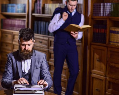 Arkadaşı okurken sakallı bir adam daktiloda daktilo yazıyor.