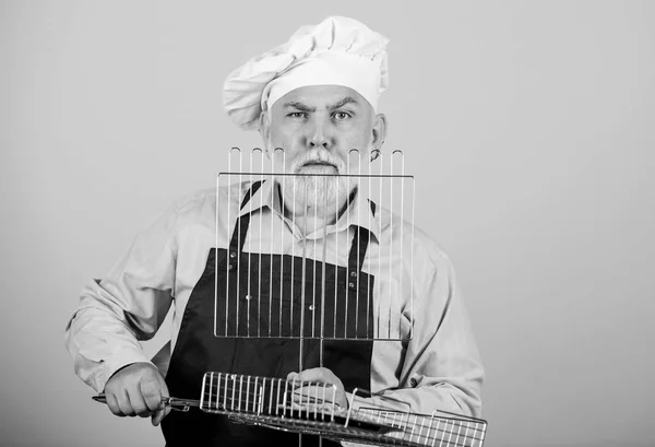 Hij geeft de voorkeur aan grillvoedsel. Picknick en barbecue. Keukenregels. Maak het eten klaar voor familie. Familieweekend. Oudere man met koksmutsen. Kook mannen met een baard. kookgerei voor de barbecue — Stockfoto