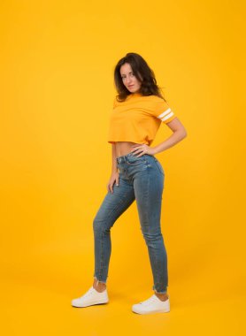 Havalı kız. Seksi kız sarı arka plan. Makyajlı ve güzel görünümlü şehvetli bir kız. Uzun esmer saçlı, sıradan tarzda güzel bir kız. Moda ve tarz