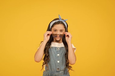 Yaz tatili. Retro çocuk uzun saçı. Küçük çocuk klasik güneş gözlüğü. Tatil modu başladı. Küçük moda düşkünü. Çocuk butiği. Retro kız. Yaz moda konsepti. Neşeli küçük kız sarı arka plan