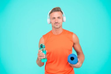 Sporcular için hidrasyon. Atlet altın su şişesi mavi arka plan. Eğitimden önce ve sonra su içmek. Su ve yoga. Egzersiz sırasında susadım. Vücut suyunu dengede tutmak