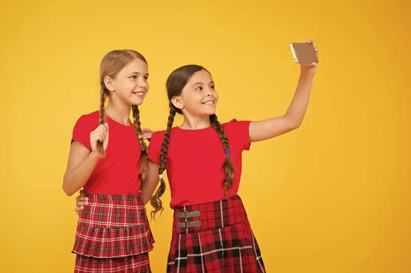 Vamos fazer pic. Raparigas fardadas. meninas pequenas fazendo selfie no telefone. a divertir-se. Irmandade e amizade. feliz dia do conhecimento. felicidade infantil. conceito de educação. de volta à escola. rede social — Fotografia de Stock