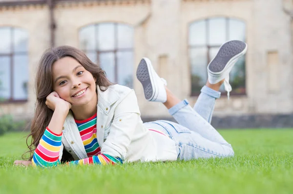 School break for rest. Adorable pupil. Girl kid laying lawn. Girl school uniform enjoy relax. Importance of relaxation. Little schoolgirl. Relax at school yard. Kid relaxing outdoors. Look at her now