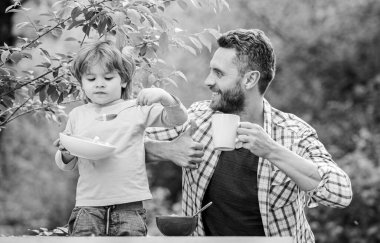 Babalar günün kutlu olsun. Babasıyla küçük çocuk mısır gevreği yiyor. Baba ve oğul dışarıda yemek yiyorlar. Sabah kahvaltısı. Aile bağları. Birlikte eğleniyoruz. Sağlıklı yemek ve diyet. Sağlıklı bir kahvaltı.