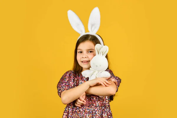 Весной. Маленькая девочка держит зайца за игрушку. Счастливого детства. милый ребенок играет с игрушкой. Концепция магазина игрушек. Девушка в смешных кроличьих ушах. С праздником Пасхи. подготовка весенних каникул. Пасхальный кролик — стоковое фото