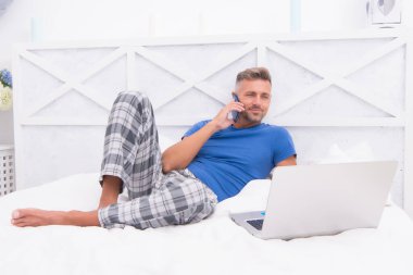 İnternette çalışıyorum. Adam dizüstü bilgisayarda çalışıyor. Online kurslar evde eğitim. İpuçlarını kilitle. Bir şeyler alıp internetten alışveriş yapmak. Adam yatakta telefonu kullanıyor. İletişim ve insan konsepti. Çevik iş. sabah titreşimleri