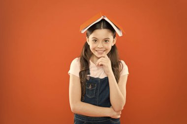 Evde eğitim ve özel ders. Kafasına kitap. Küçük kız kitap çatı başkanı. Küçük kız kitap turuncu arka plan. Çocuk için ilginç bir hikaye. Çalışmak ve dinlenmek. Evde çalış. Ev ödevi konsepti