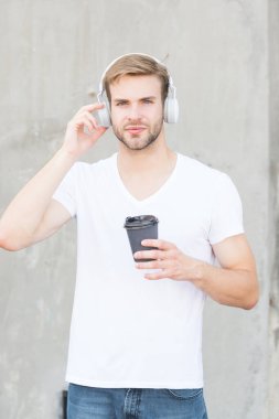 Kahve tüketimi onu daha mutlu ediyor. Yakışıklı adam kağıt bardak yapmak için kahve içer. Kafe konsepti. Kahve dükkanı. Adam taze demlenmiş kahveyi seviyor. Günlük kafein miktarı. Müzikle yürümek. Parçayı atla