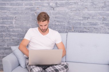 Sosyal uzaklık. Adam bilgisayarda çalışıyor. Çevrimiçi kurslar. Evde eğitim. İnternetten alışveriş. Adam bilgisayar gevşetici kanepe kullanıyor. Çevrimiçi iletişim kavramı. Evden çalışıyorum. Kendini soyutlama. Evde kal.