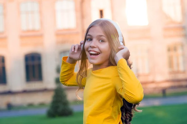 Son stéréo. J'écoute de bonnes histoires. Auto-éducation. Casque avec technologie sans fil. Petit enfant écoutant de la musique écouteurs modernes. Apprentissage à distance. Joyeux petite fille portant des écouteurs — Photo