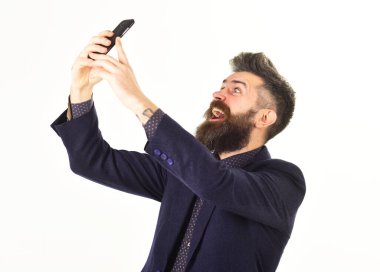 Orta yaşlı bir adam elinde akıllı bir telefonla görüntülü konuşma yapıyor.