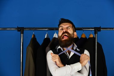 Acı çeken yüzlü terzi boynunda şerit tutuyor.