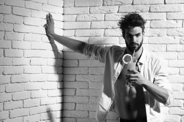 Beyaz tuğla duvarda yakışıklı, sakallı, maço seksi bir adam.