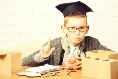 Sınıfta beyaz tuğlalı duvarda küçük sevimli bir öğrenci var.