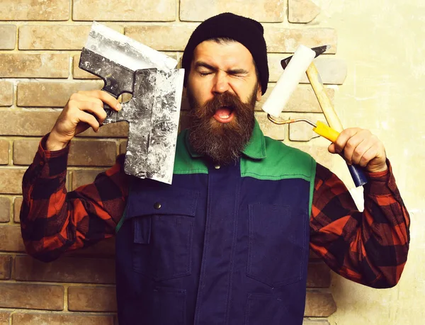 Бородатый художник держит различные строительные инструменты с довольным лицом — стоковое фото