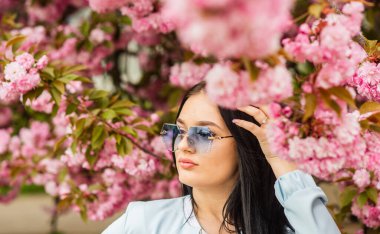 Seksi kız sakura çiçeğinin tadını çıkarıyor. Kiraz çiçekli kadın. Kadın kiraz çiçeklerini geziyor. Bahar mevsiminde seyahat. Kiraz çiçekli bahar kadını çiçek açıyor. kız sakura konsepti