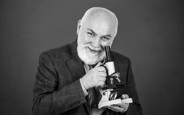 Sabedoria. Biologia equipamentos de laboratório da escola. Homem na sala de aula no quadro negro. professor sênior feliz usar microscópio. química no laboratório da escola. experimentos científicos com microscópio em laboratório — Fotografia de Stock