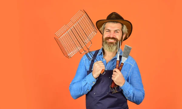 Biefstuk en barbecue. Barbecue menu. Baard hipster dragen hoed en schort voor barbecue. Eten grillen. Amerikaanse picknick. Familietraditie. Voorjaarsseizoen. Vlees aan het koken. Vlees roosteren. Picknick en barbecue — Stockfoto